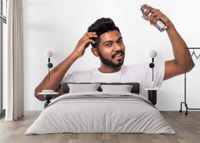 Young indian man with a beard on a grey isolated background purrs a hair spray. Beauty concept. Wall mural